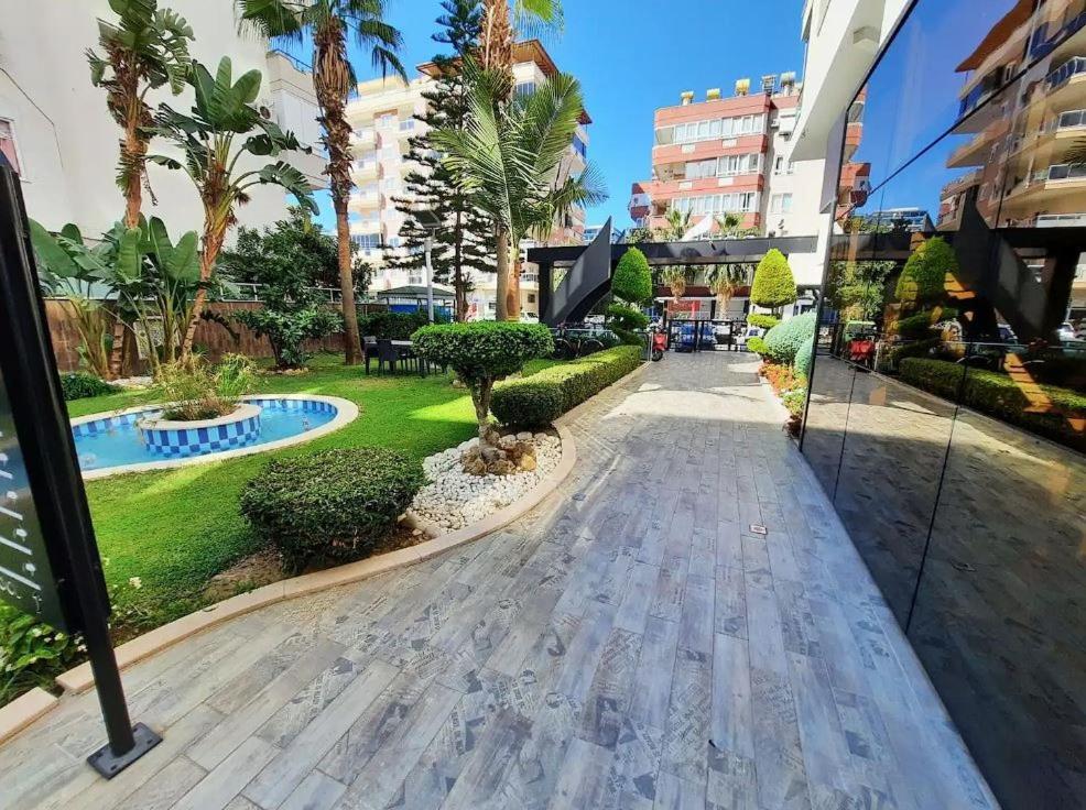 einen Gehweg durch einen Park mit Palmen und Gebäuden in der Unterkunft Luxury Apartment Mahmutlar in Mahmutlar