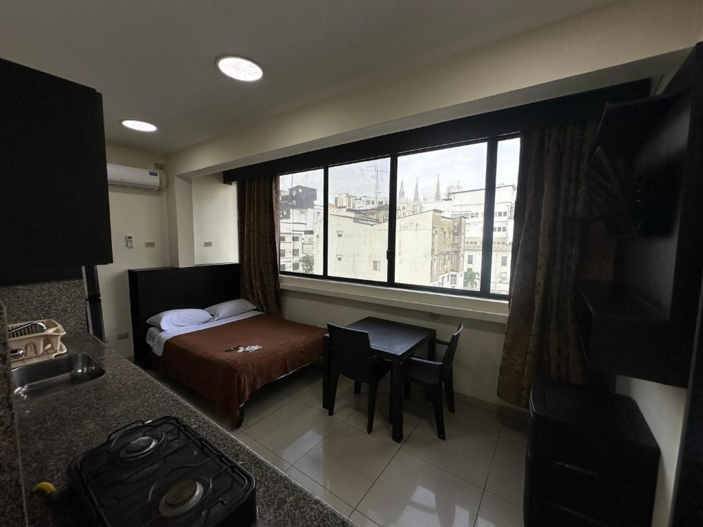 1 dormitorio con cama, mesa y ventana en Residencia Terreros, en Guayaquil