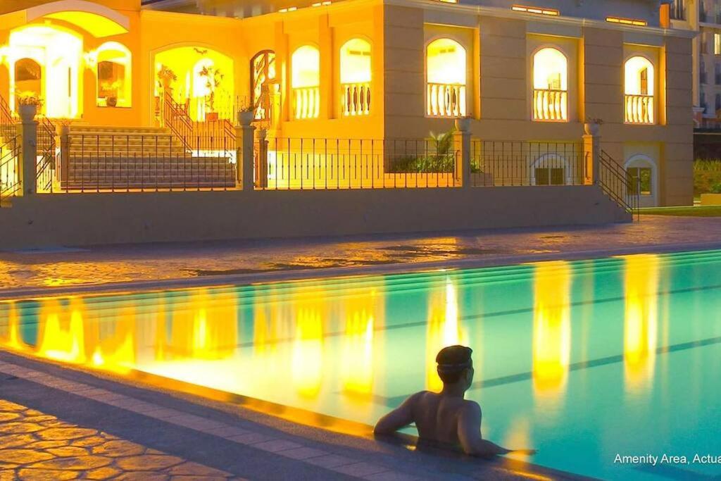 una persona sentada junto a una piscina por la noche en Chateau Elysee A21 near Airport,bar,Resto, en Manila