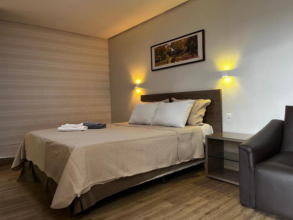 1 dormitorio con 1 cama con sofá y silla en Flat 1209 - Conforto Parque Areião, en Goiânia