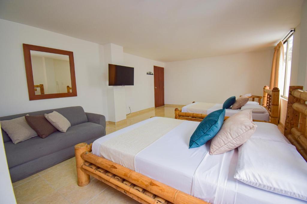 a bedroom with two beds and a couch at Hotel Toledo Plaza in Armenia