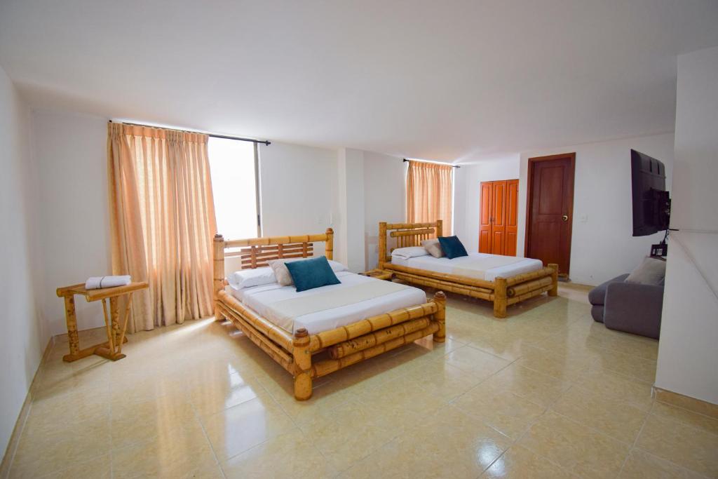 a bedroom with two beds and a tv and a couch at Hotel Toledo Plaza in Armenia