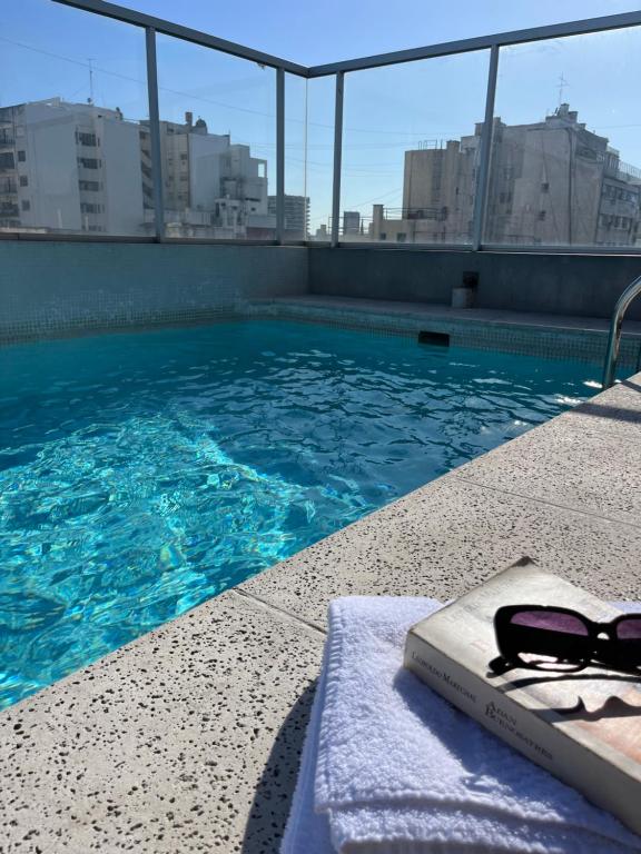 a swimming pool with a book and a pair of sunglasses at Dumont Urban Studio in Buenos Aires