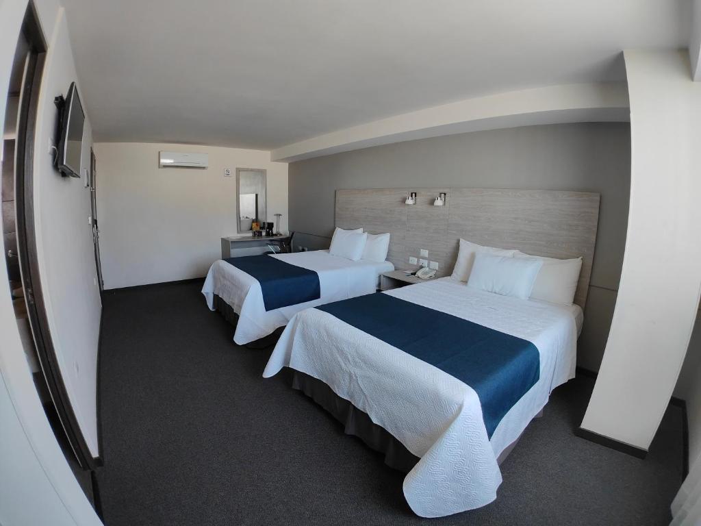 Habitación de hotel con 2 camas y escritorio en Kasa Hotel & Suites, en Irapuato