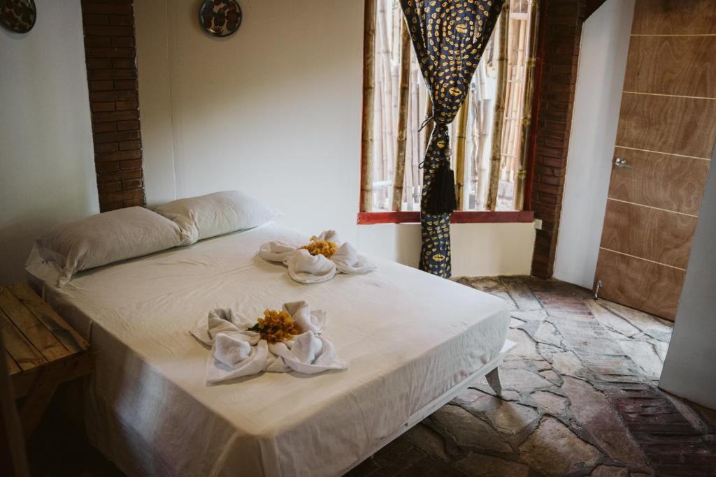 a bed with flowers on it in a room at Caracolito Hostal in Las Peñitas