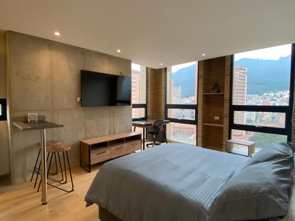 a bedroom with a bed and a desk and a television at PENTHOUSE Centro Internacional Apartamento in Bogotá