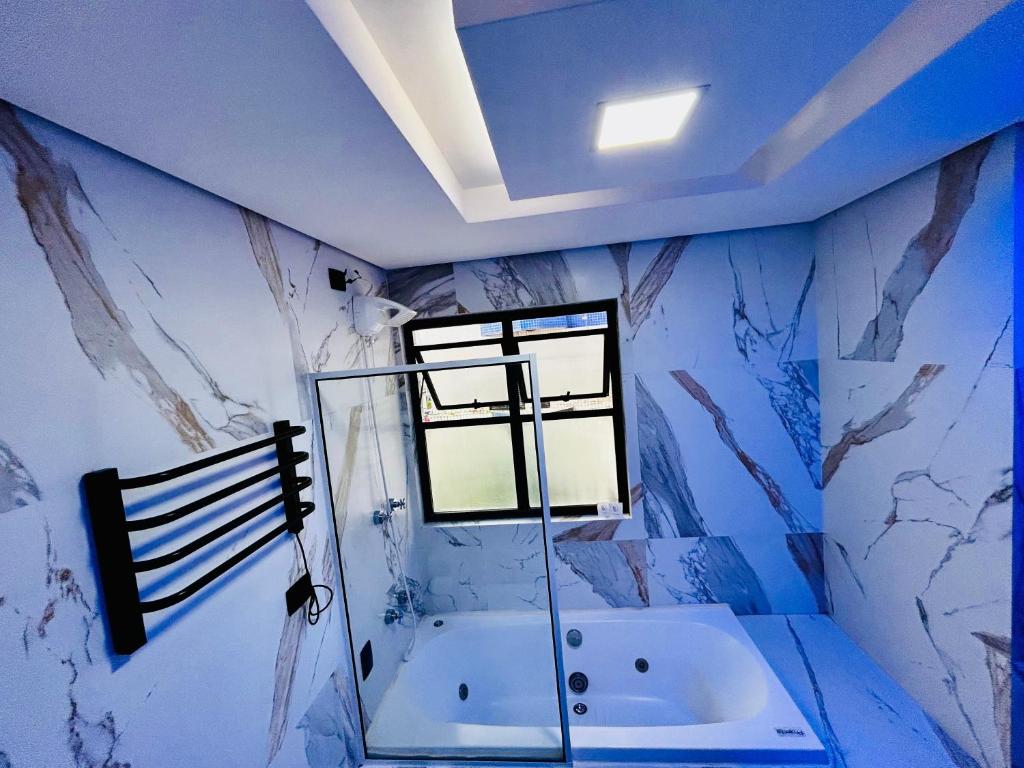 a bathroom with a tub and a window at Flat -Hidromassagem privativa e Piscina a 500 mts da praia in São Vicente