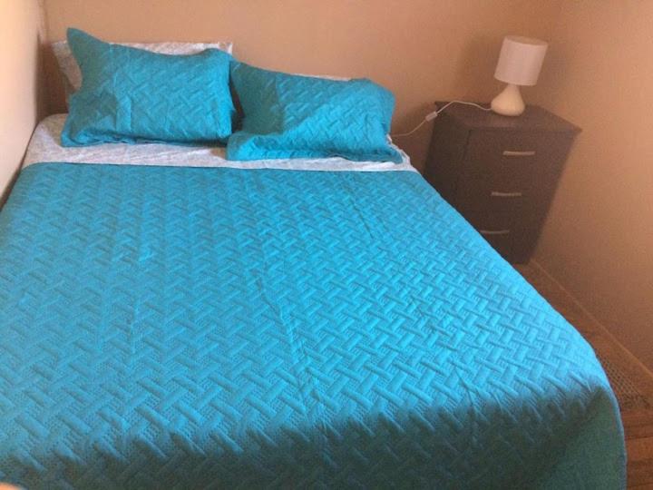 1 cama con edredón azul y almohadas azules en Cabañas Miraflores ubicadas en zona central de punta de choros a una cuadra de la playa de punta de choros, en Choros