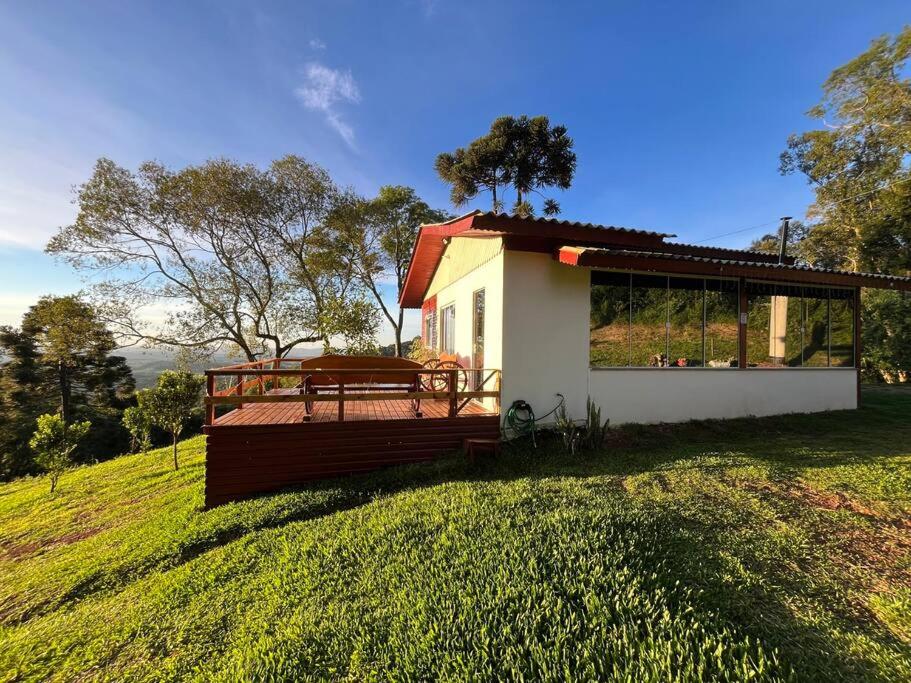 a house with a deck with a bench on a field at Cabana recanto dos ipês 