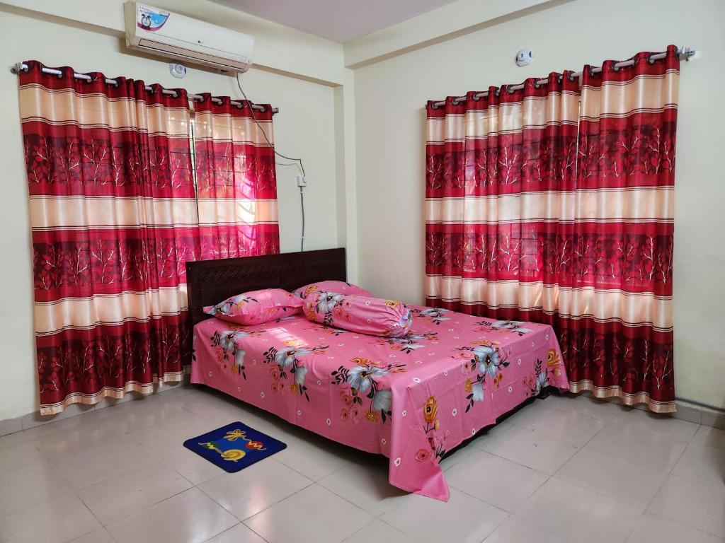 a bedroom with a pink bed and red curtains at Aaira guest house in Dhaka