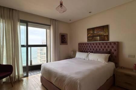 a bedroom with a large bed and a large window at Marina Urban Sea View - By AppartAli in Casablanca
