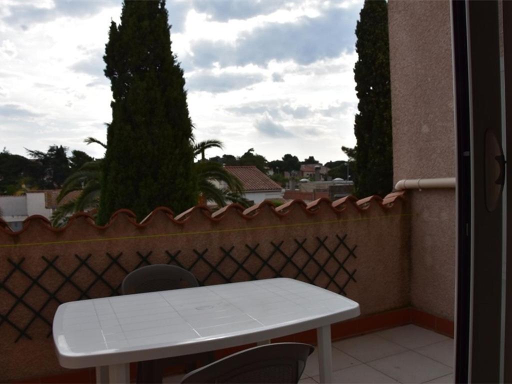 une table et des chaises blanches sur un balcon arboré dans l'établissement Appartement Duplex Climat' 3 pièces, proche plage à Argelès, terrasse, parking, WIFI, 6 pers - FR-1-776-1, à Argelès-sur-Mer