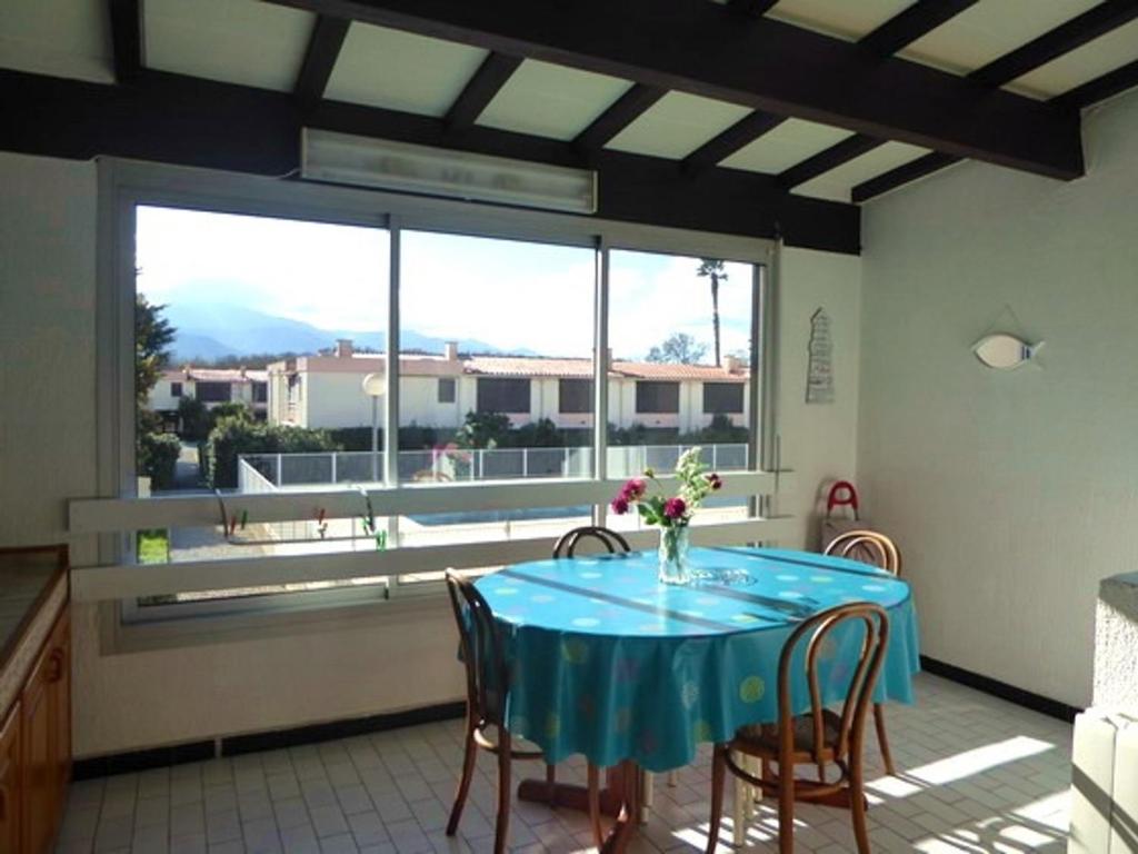une salle à manger avec une table bleue et une grande fenêtre dans l'établissement Appartement T2 confortable avec piscine, tennis, à 500m de la plage d'Argelès-sur-Mer, pour 4 pers - FR-1-776-41, à Argelès-sur-Mer