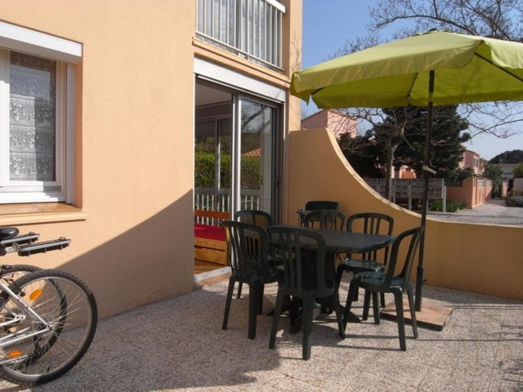 una mesa, sillas y una sombrilla en el patio en Appartement Argelès-sur-Mer, 2 pièces, 4 personnes - FR-1-776-43, en Argelès-sur-Mer