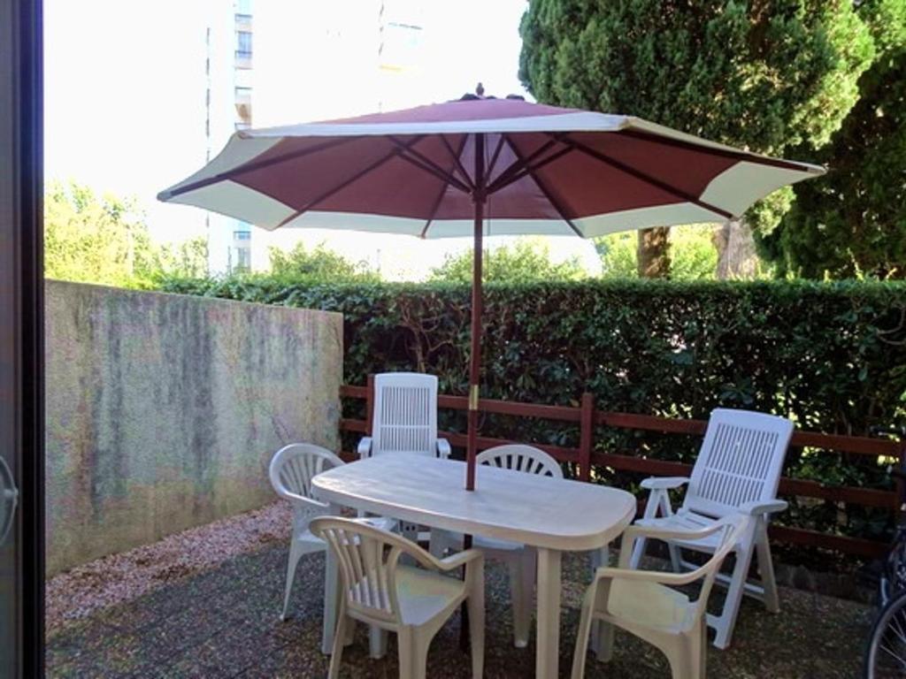 une table et des chaises blanches avec un parasol dans l'établissement T2 avec Terrasse à 500m de la Plage - Piscine, Tennis, Parking Privé - Argelès-sur-Mer - FR-1-776-40, à Argelès-sur-Mer