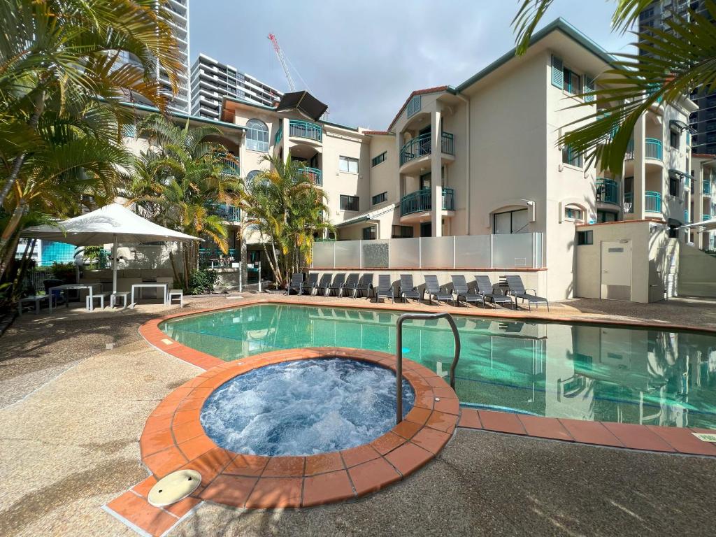a swimming pool with a hot tub in front of a building at CHA Private Apts Aruba Beach in Gold Coast