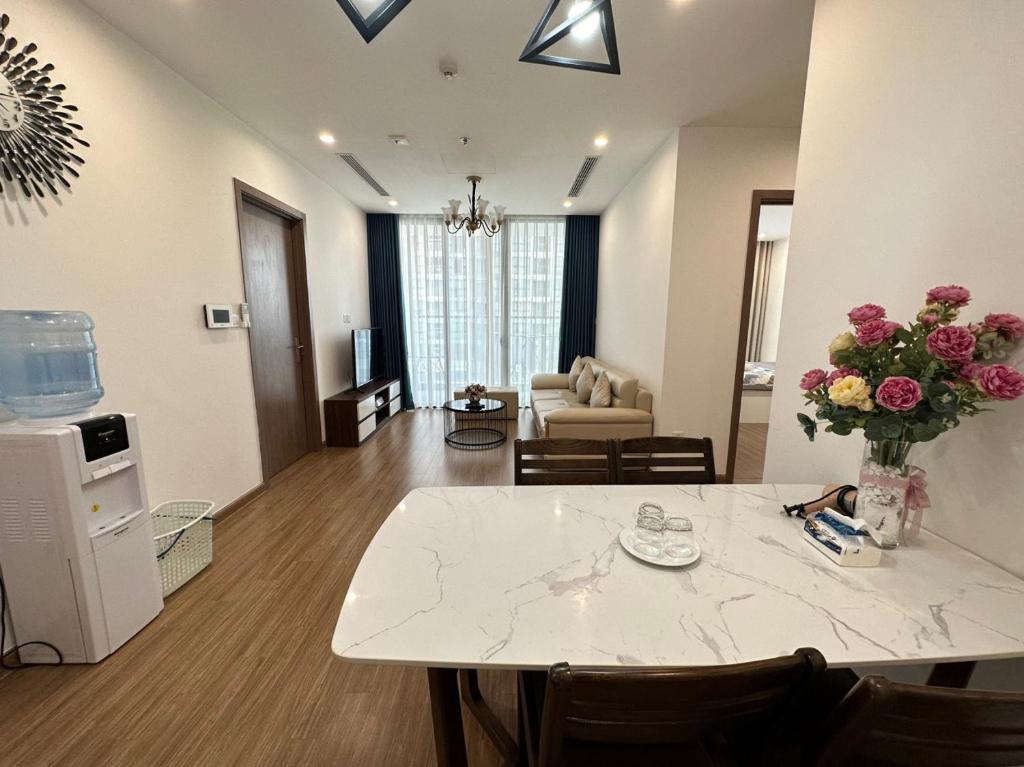a living room with a table with a vase of flowers at Vinhomes Sky Lake Phạm Hùng View Keangnam in Hanoi