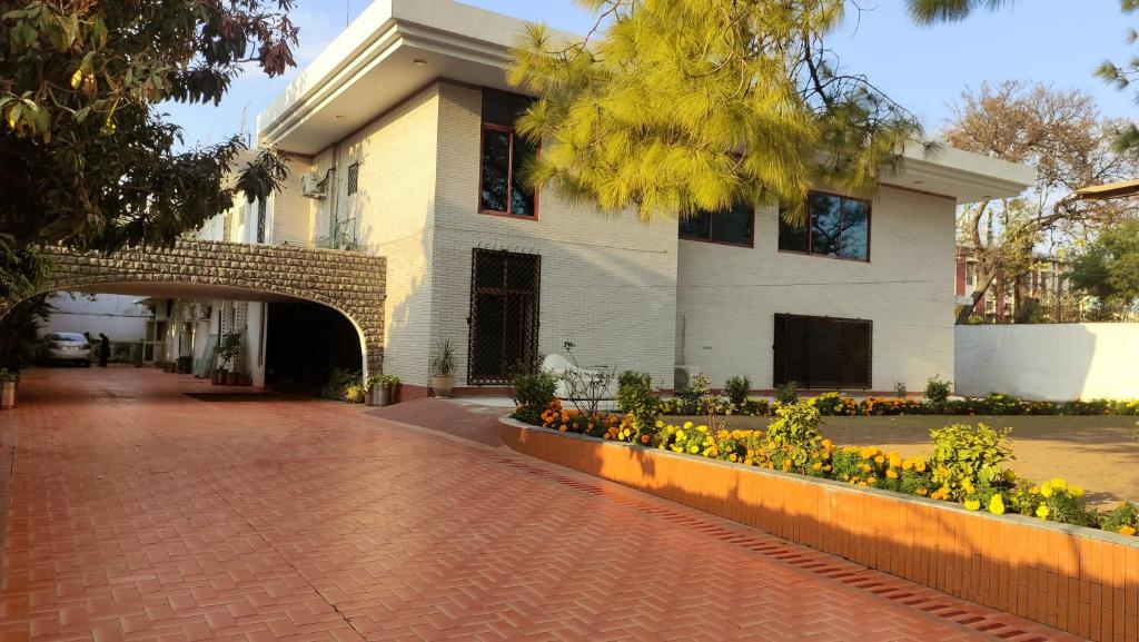 a building with a brick walkway and flowers in front of it at Aleph Islamabad Guest House in Islamabad