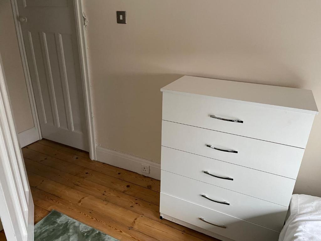 a white dresser in the corner of a bedroom at B&B in Luton