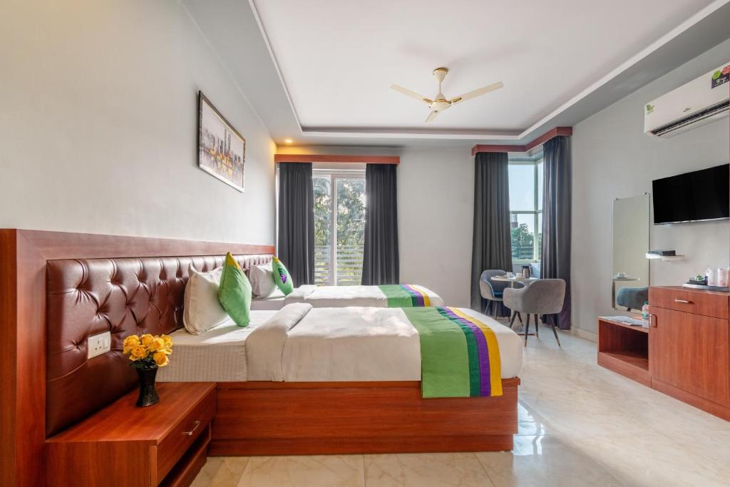 - une chambre avec un grand lit et une télévision dans l'établissement Treebo Trend Expo Mart Inn - Greater Noida, à Greater Noida