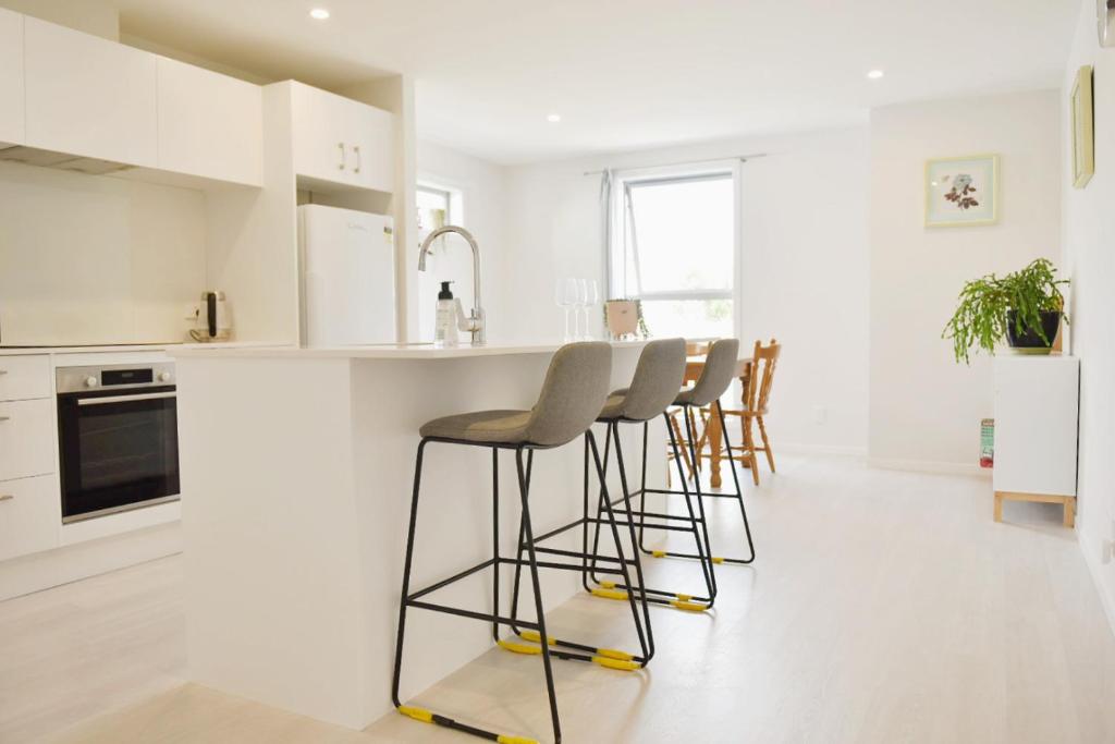 a kitchen with white cabinets and bar stools at Johnsonville Brand New Lovely townhouse in Wellington