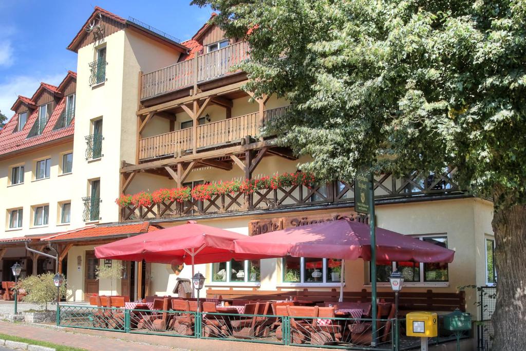 ein Restaurant mit Tischen und Sonnenschirmen vor einem Gebäude in der Unterkunft Hotel am Liepnitzsee in Wandlitz