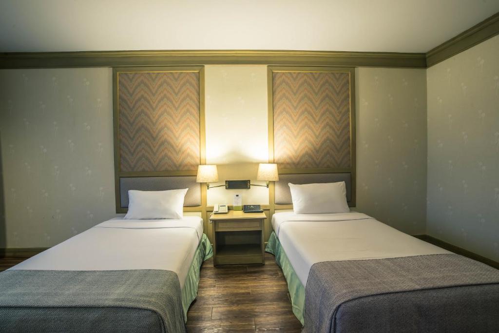 um quarto de hotel com duas camas e uma secretária em โรงแรมมุกดาหารแกรนด์ 