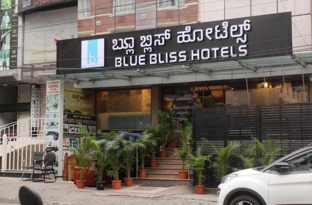 a blue bus hotel with plants in front of it at Blue Bliss Hotels By PPH Living Infantry Road in Bengaluru