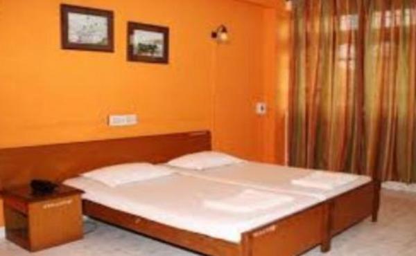 een bed in een slaapkamer met een oranje muur bij Vasco Residency in Vasco Da Gama