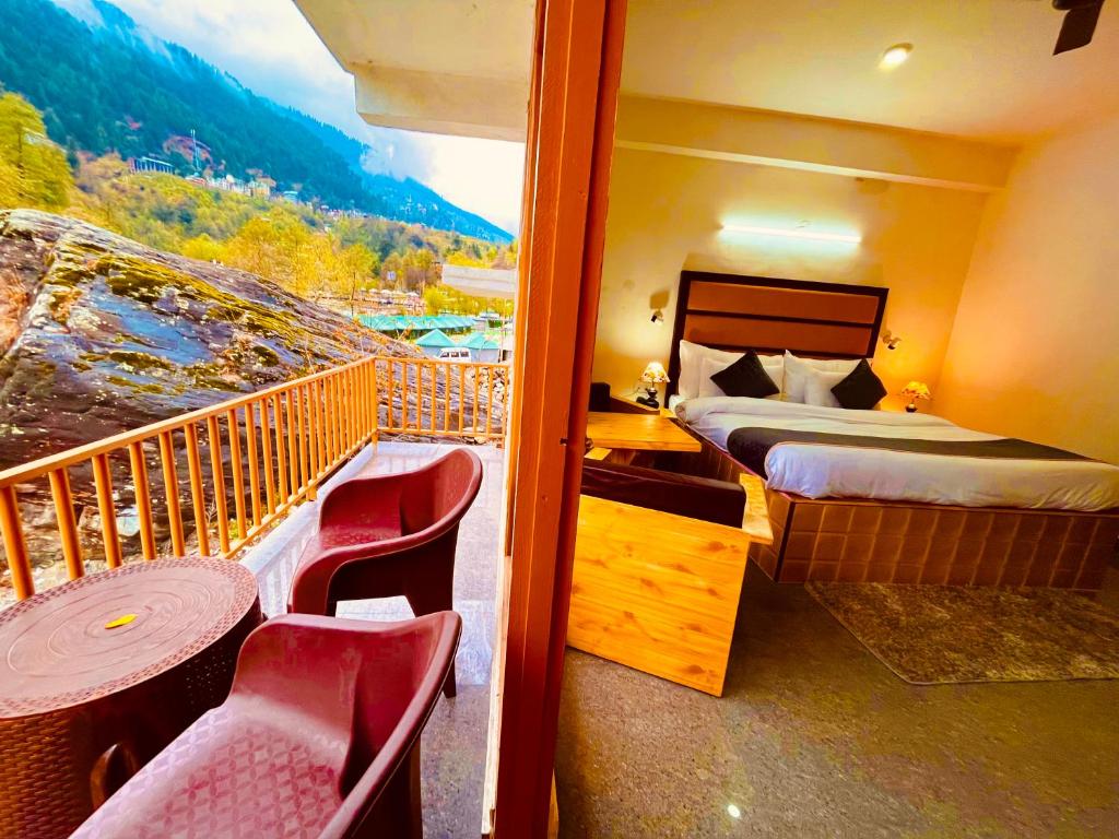 a hotel room with a balcony with a bed and chairs at Manali Hotel Beas River Retreat in Manāli