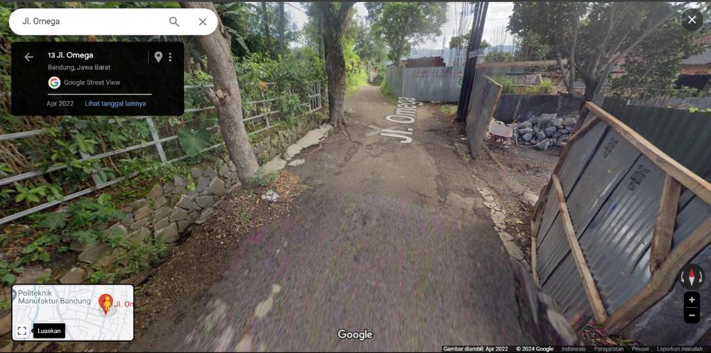 a dirt road with a sign and a fence at Ucil Party House in Bandung
