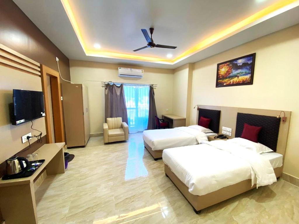 Cette chambre comprend deux lits et une télévision. dans l'établissement GRACE INN GUEST HOUSE, Near Airport and Ion Digital, à Guwahati