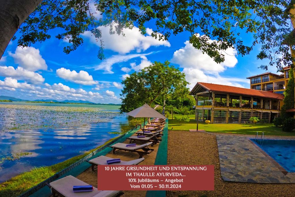 a row of lounge chairs next to a lake at Thaulle Pure Ayurveda Resort - Yala in Tissamaharama