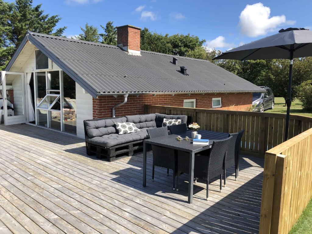 una terraza con sofá, mesa y sombrilla en Summerhouse Near The Limfjord And The Western Sea en Vestervig