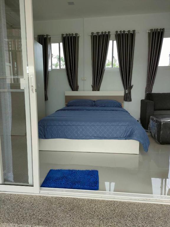 a bedroom with a bed with blue sheets and windows at Nongnuchs Homestay Queen Bed in San Sai