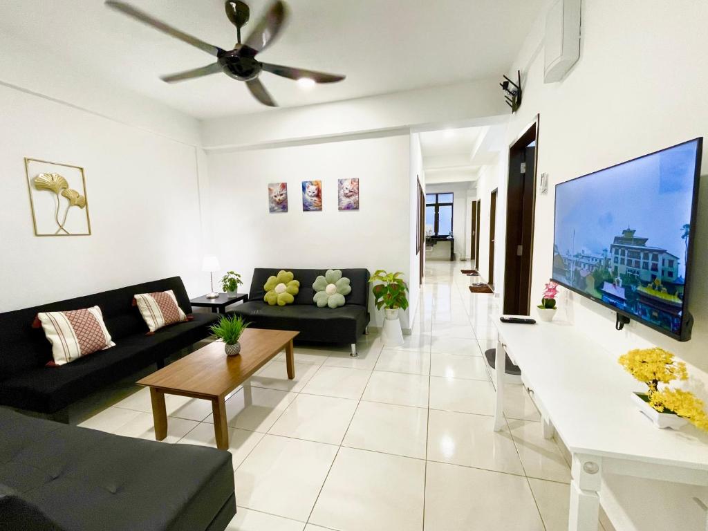 ein Wohnzimmer mit einem schwarzen Sofa und einem Flachbild-TV in der Unterkunft The Urban Lodge 1 in Kuala Terengganu