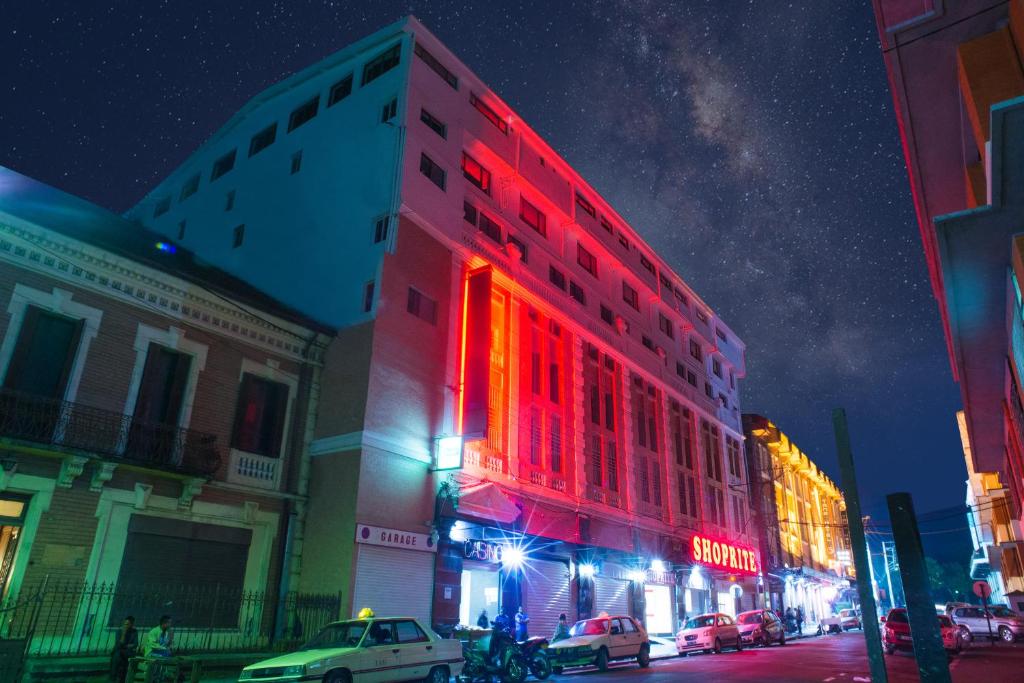 un bâtiment avec des lumières rouges sur une rue de la ville la nuit dans l'établissement Hotel Le Pousse Pousse, à Antananarivo