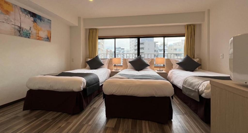 um quarto com 4 camas e uma grande janela em Le Tour Hotel Akihabara Kandai 楽途ホテル神田秋葉原 em Tóquio