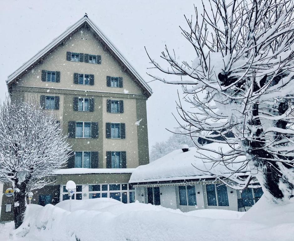 un grande edificio ricoperto di neve accanto agli alberi di Hotel Stätzerhorn a Parpan