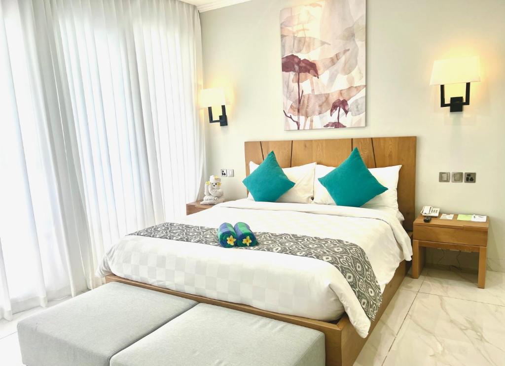 a bedroom with two beds with blue pillows at The Bay Sunflower Apartment in Nusa Dua