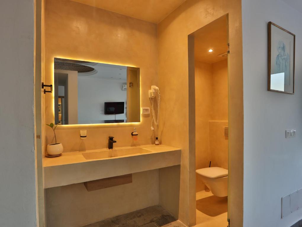 a bathroom with a sink and a mirror and a toilet at Dar Souad in La Marsa
