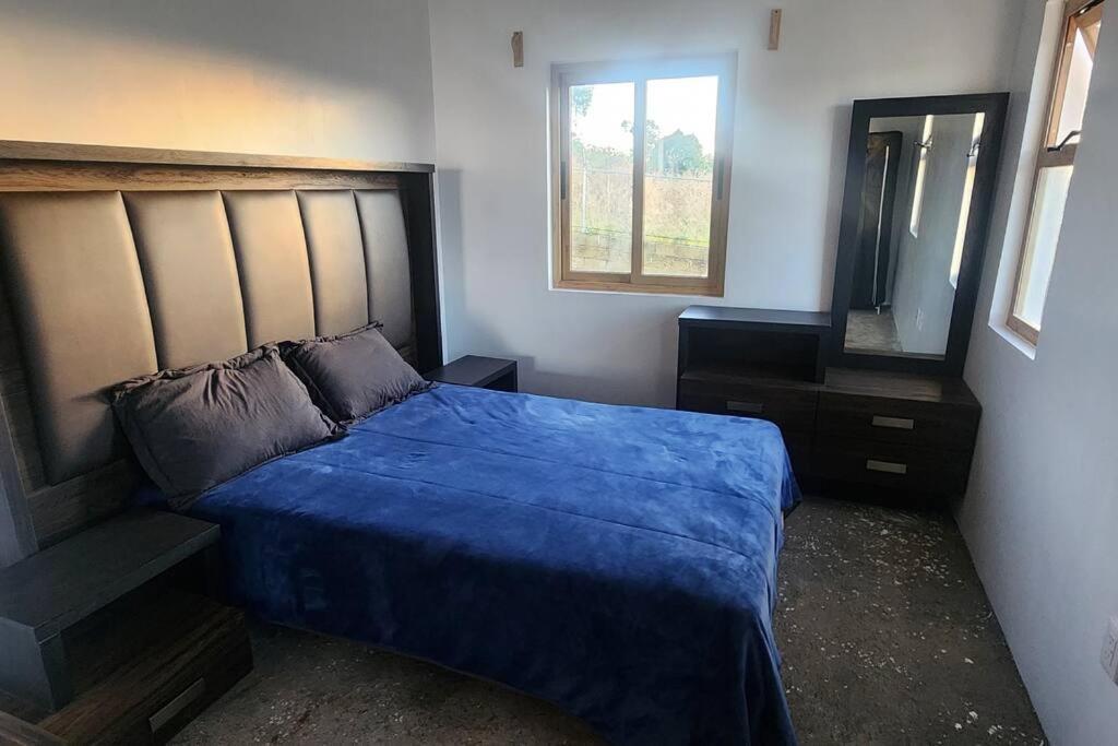1 dormitorio con cama azul y espejo en Terraza, Casa, Cabaña, Campo, en Arandas