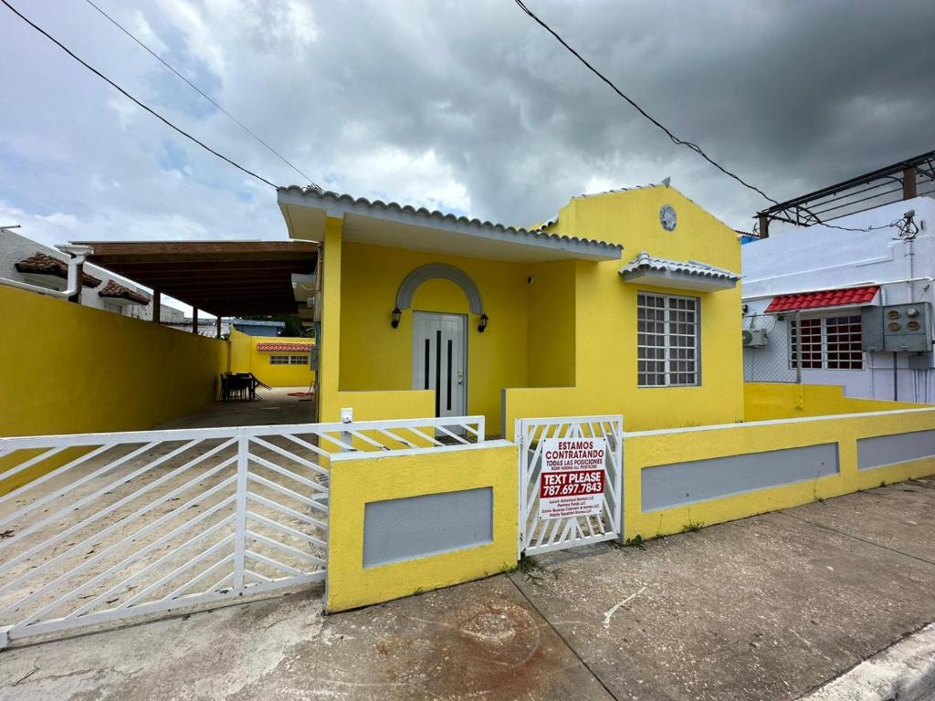 una casa amarilla con una puerta delante de ella en Best Surfers Beach just a few block down, Arecibo Main House, en Arecibo