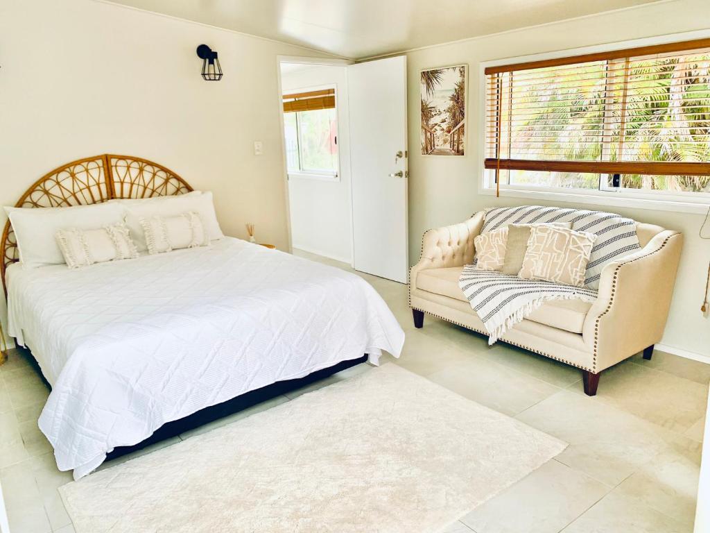 a bedroom with a bed and a couch and a window at Deluxe Queen Studio Fully Self Contained- Living, kitchenette, laundry, bedroom, bathroom, parking, Wifi, - Free shuttle Service in Gold Coast