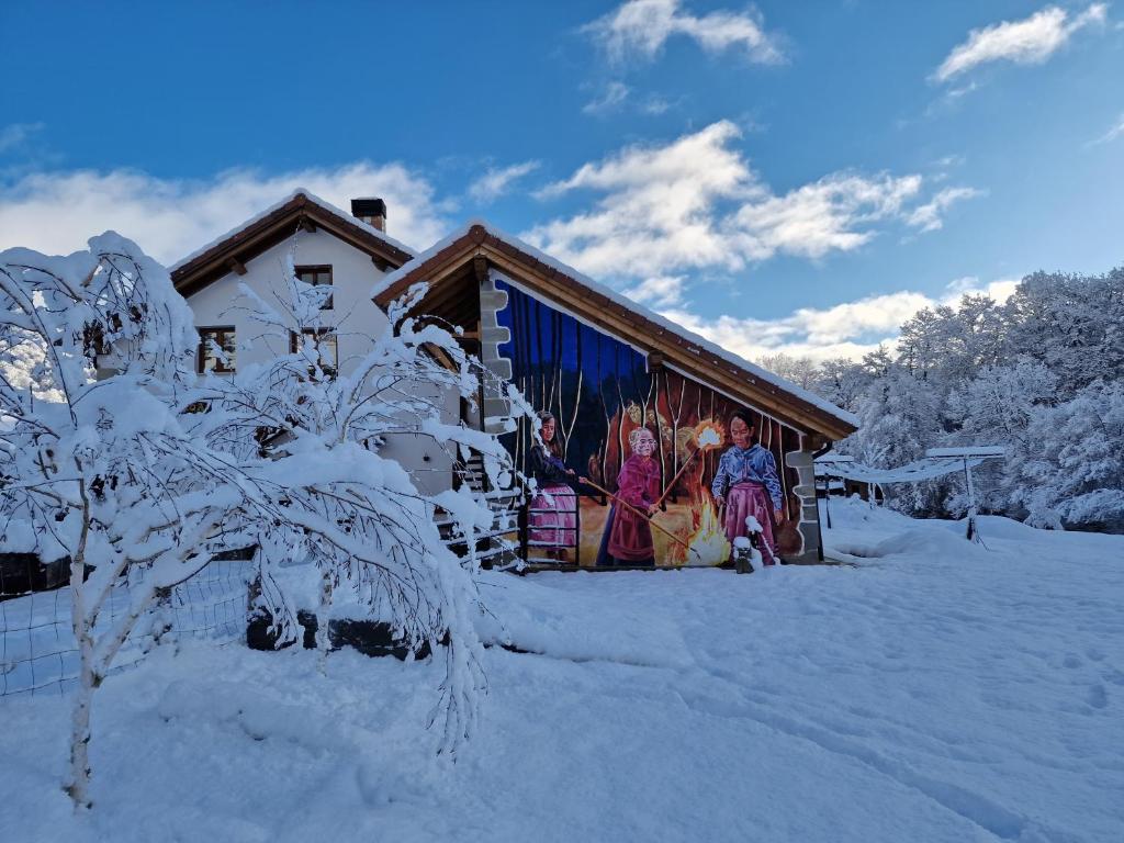 dos personas parados fuera de una casa en la nieve en Hostal Rural Iratiko Urkixokoa en Orbaiceta