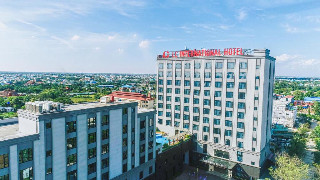 un edificio blanco alto con un cartel encima en LC International Hotel, 