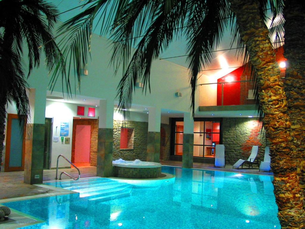 a swimming pool with a palm tree next to a building at Burton Hotel in Kington