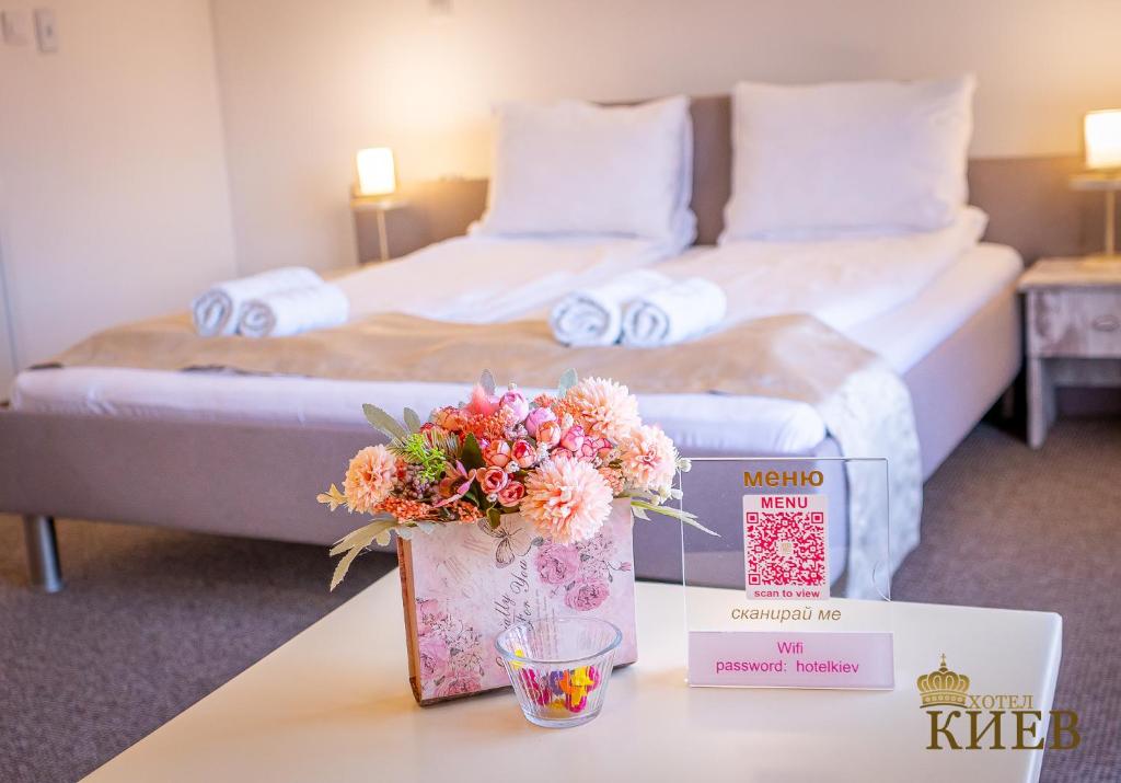 a hotel room with a bed and a table with flowers at Hotel Kiev in Veliko Tŭrnovo