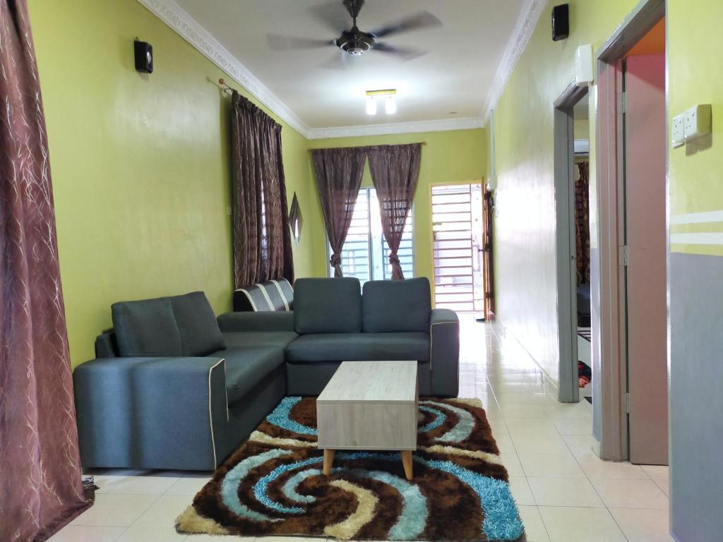 a living room with a blue couch and a table at RIZQI HOMESTAY Sungai Siput with Wifi! Islamic Guest Only! in Kampong Rimba Panjang