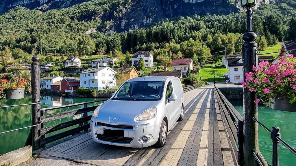 una macchina bianca parcheggiata su un ponte sopra un fiume di Electric Minicamper blue ad Askøy